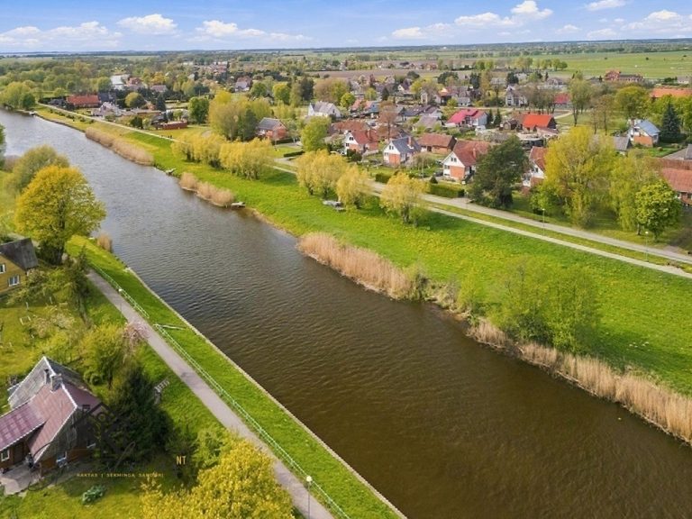 ERDVUS NAMAS SU 16.5 A ŽEMĖS SKLYPU, SODU IR VAIZDU Į PAKALNĖS UPĘ – PUIKI GALIMYBĖ ĮSIKURTI GAMTOS APSUPTYJE RUSNĖJE!